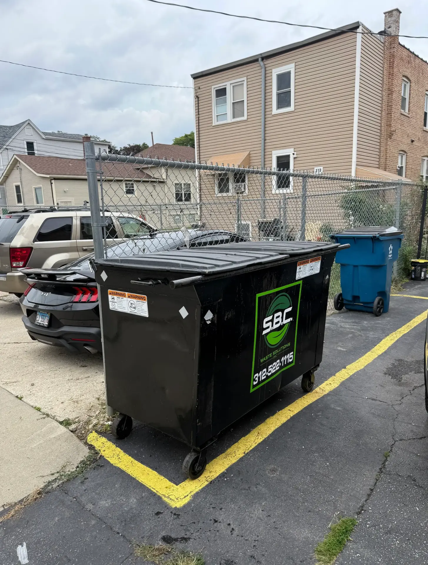 The same dumpster emptied, closed, and the area cleared after Junk Jaws service.