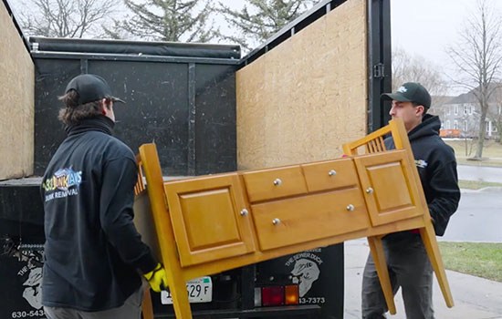 Two guys load a desk into a truck.