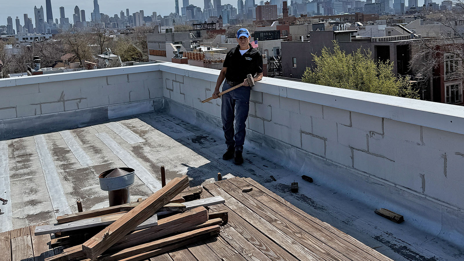 Rooftop deck removal on a Chicago building with the city skyline behind.