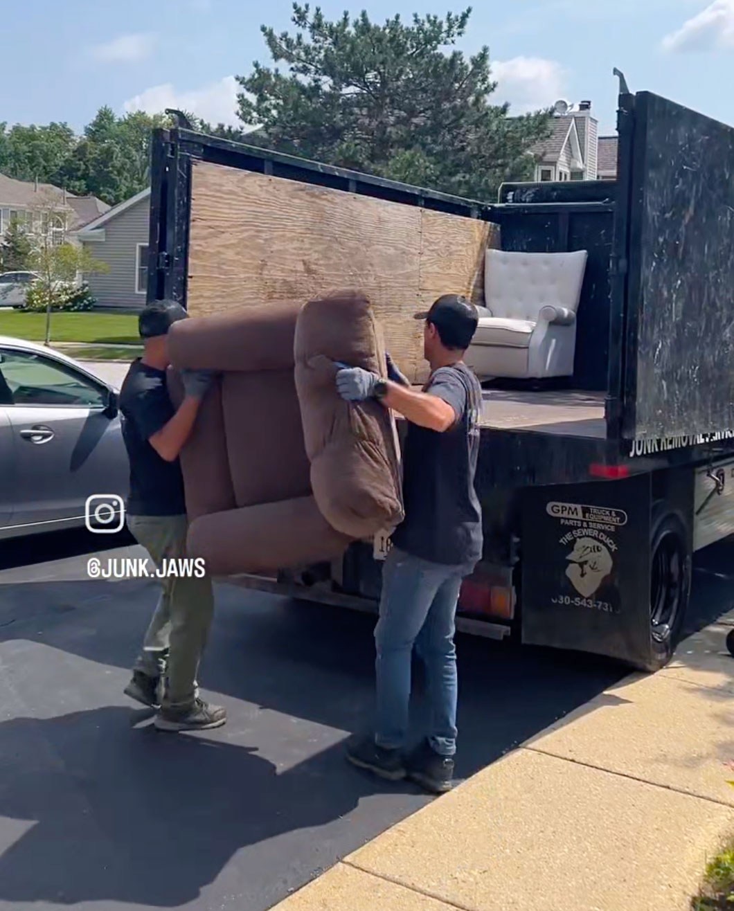Two Junk Jaws crew members carrying furniture out to the truck during a Chicago pickup.