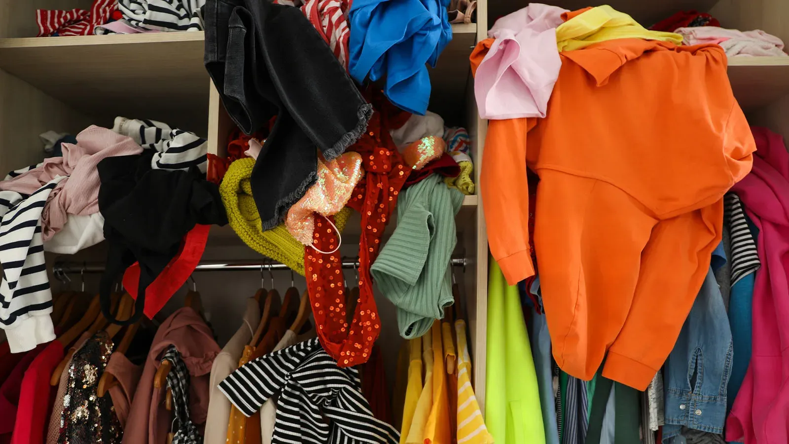A cluttered closet full of clothes and boxes