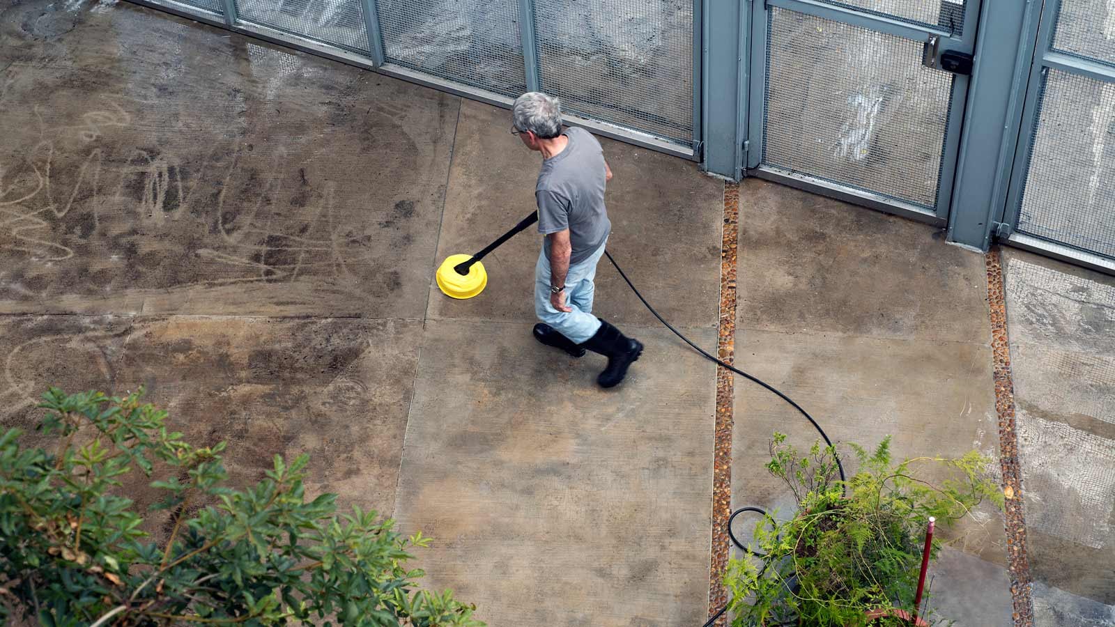 A technician pressure washing a commercial building wall