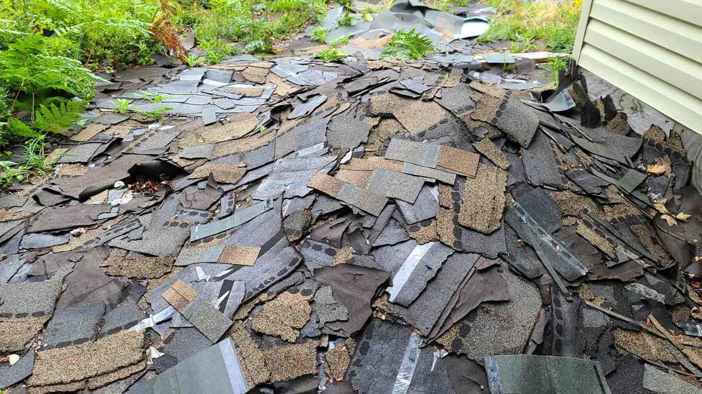 A driveway covered in torn-off roofing shingles awaiting disposal