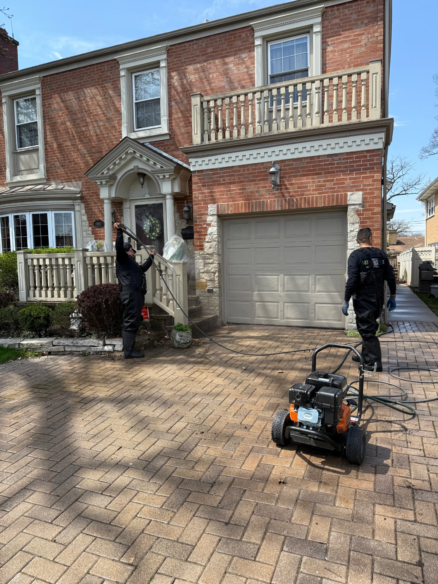A Junk Jaws crew member pressure washing a brick driveway.