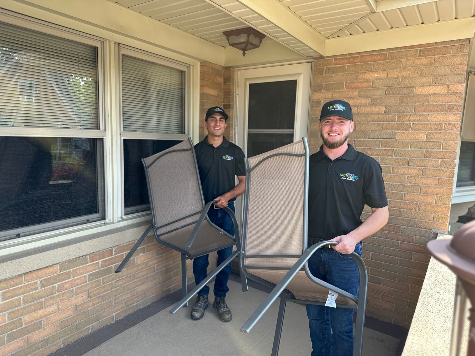 Two Junk Jaws team members carrying patio chairs out of a Chicago home.