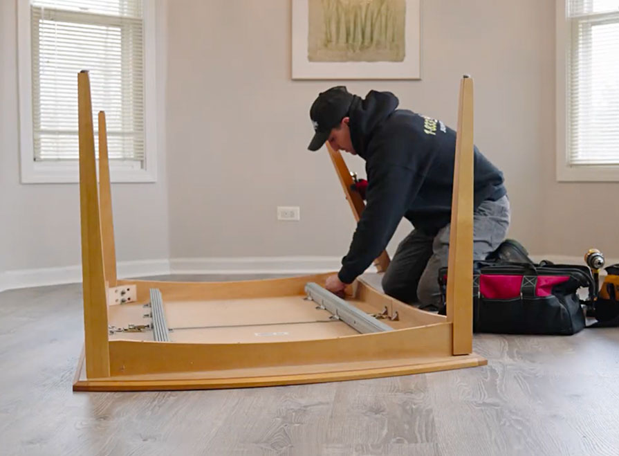 A Junk Jaws crew member disassembling a dining table on site