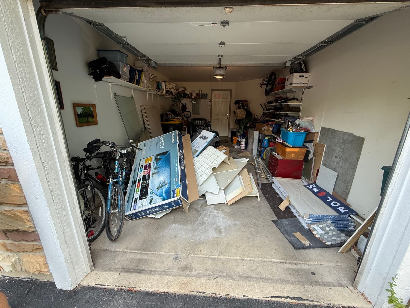 A cluttered garage packed with bikes, boxes and construction leftovers before a cleanout.