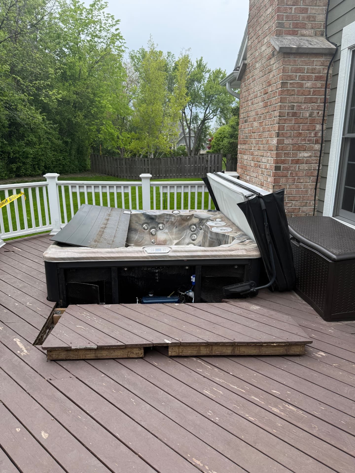 An older hot tub with its cover removed on a backyard deck before Junk Jaws hauls it away.