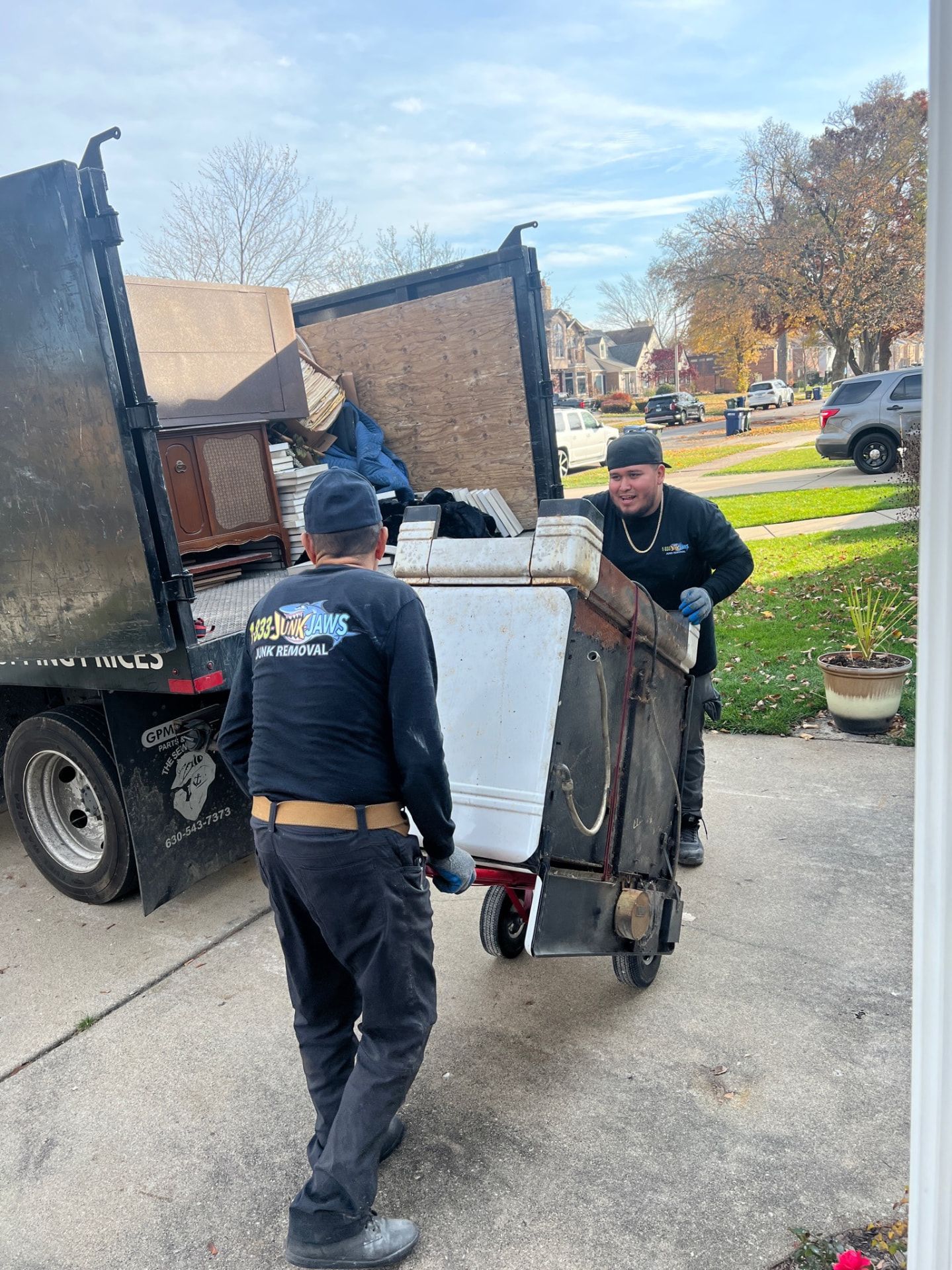 Two Junk Jaws crew members wheeling an old appliance to their truck.
