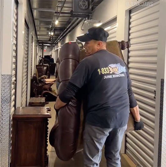 A Junk Jaws crew member carrying a couch out of a Chicago home