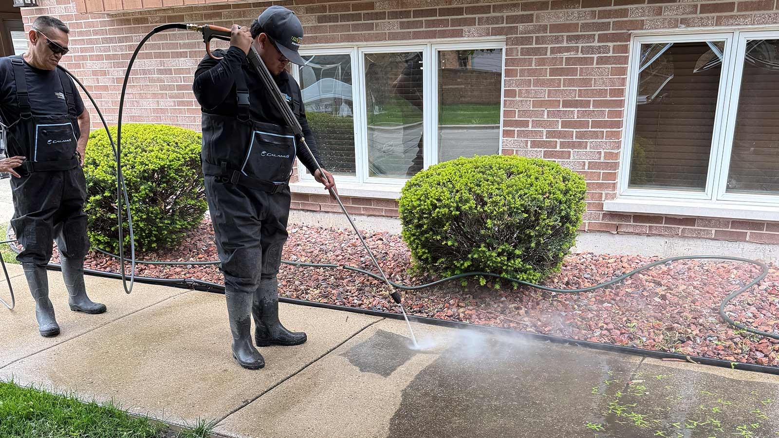 A Junk Jaws technician power washing a house exterior and walkway