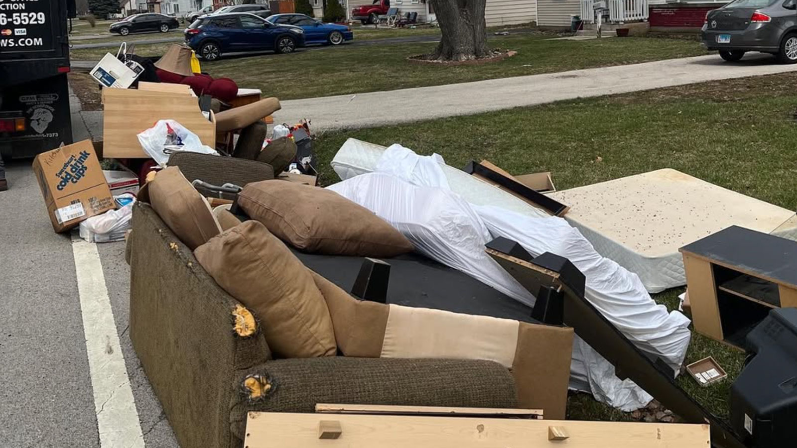 A fully loaded Junk Jaws truck is parked on the street in front of a home they just finished cleaning out.