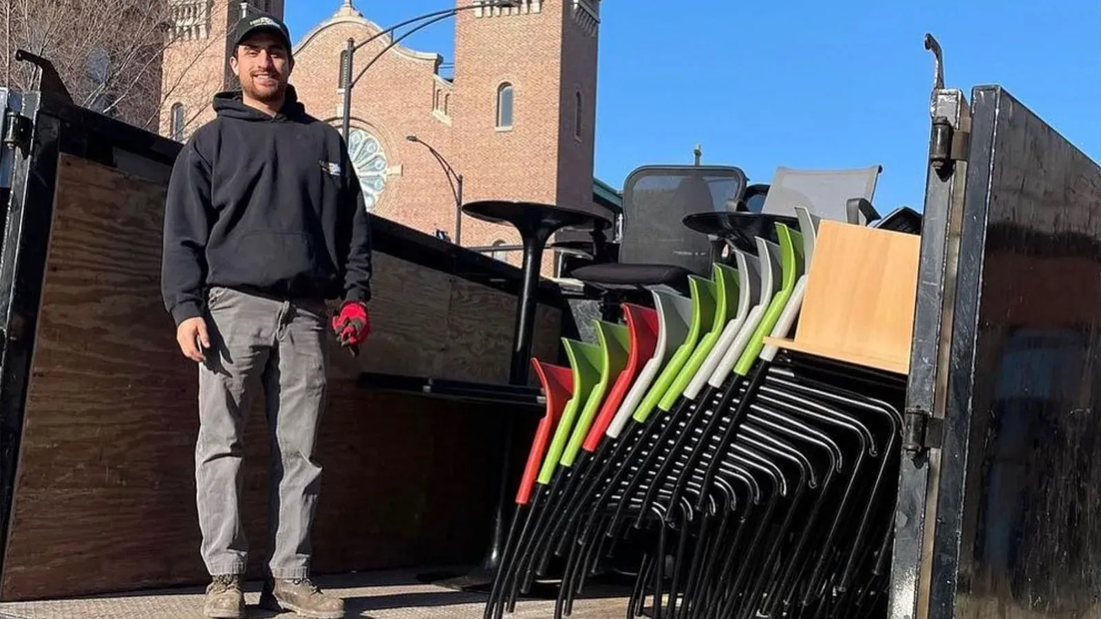 Joe from Junk Jaws stands in the bed of a truck next to a pile of office furniture.