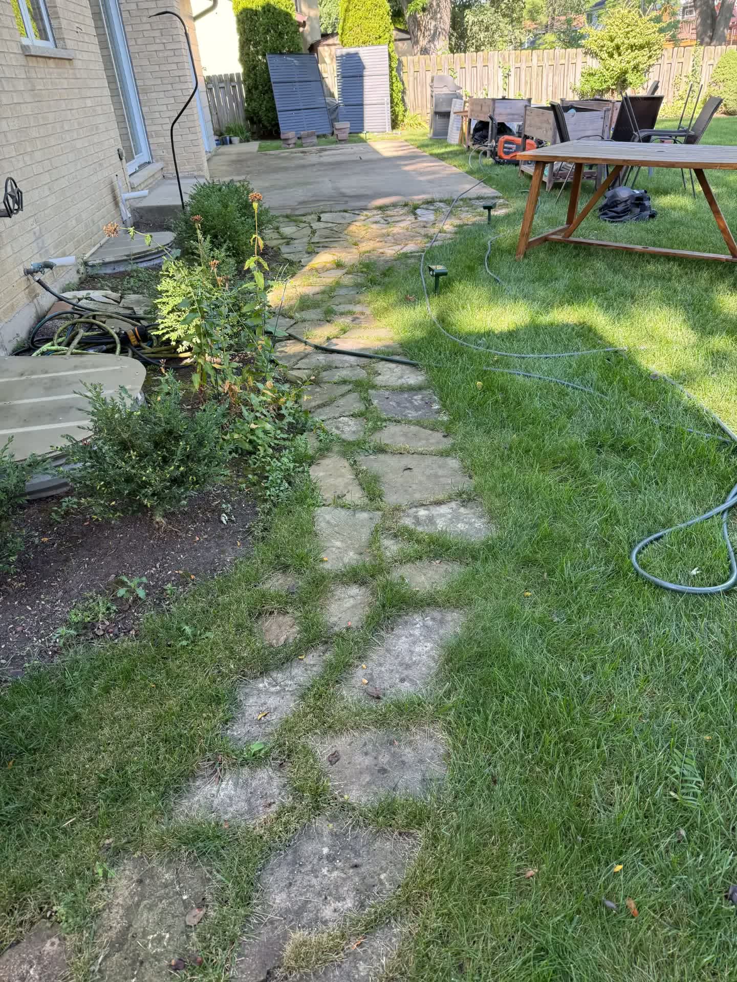 A stone walkway and concrete patio covered in dirt and growth before washing.