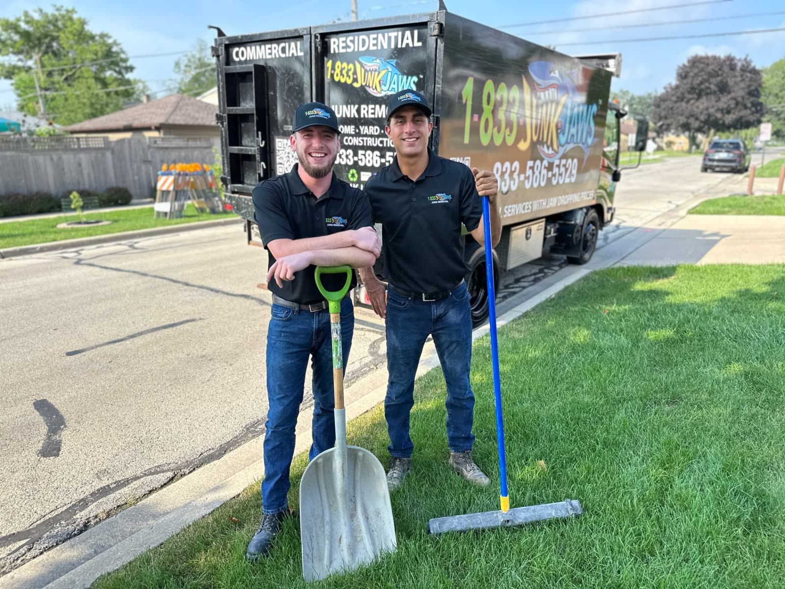 Two Junk Jaws crew members with a shovel and rake beside their truck on a Chicago lawn.